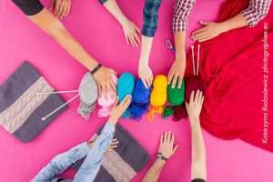 plusieurs mains sont posées sur des pelottes de laine